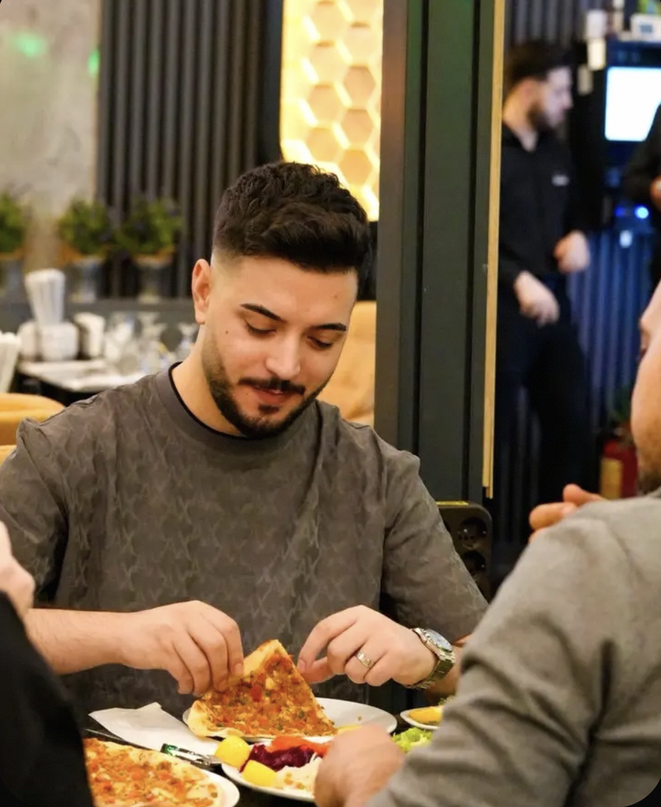 Oaspete Konak savurând un lahmacun la masă